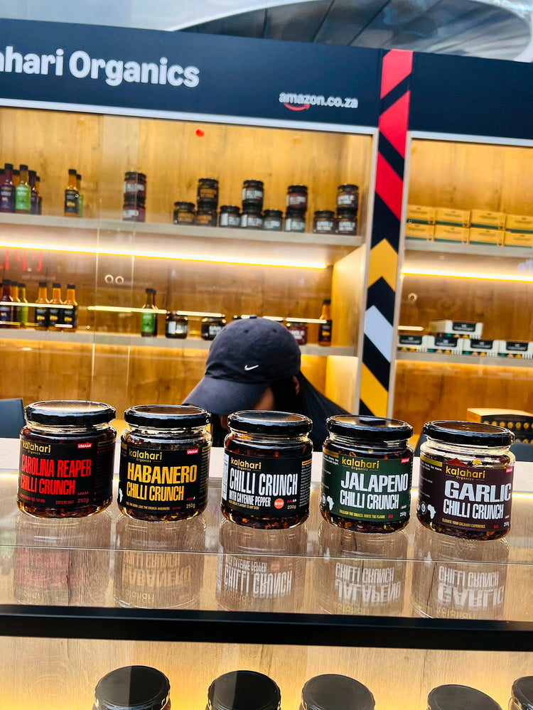 Five Kalahari Organics chilli crunch jars lined up at the pop-up: Carolina Reaper, Habanero, Cayenne, Jalapeño and Garlic
