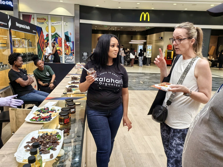 A Kalahari Organics team member talking a shopper through a tasting